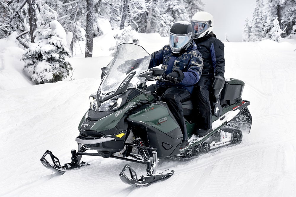 Two People Riding On A Snowmobile In The Snow